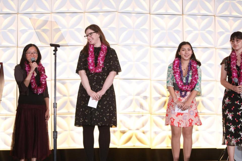 Lynn Yamasaki, Sohayla Pagano, Nina Nakao, and Jenna McGuire on stage encouraging guests to donate to the Bid for Education